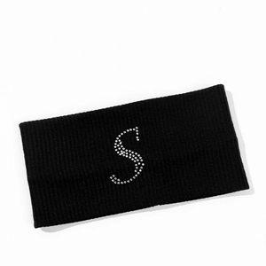 Detail of black ribbed knit sports headband featuring a sparkling rhinestone letter S