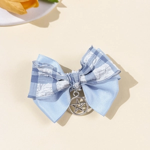 Détail de la pince à cheveux noeud en satin bleu avec un pendentif étoile argentée