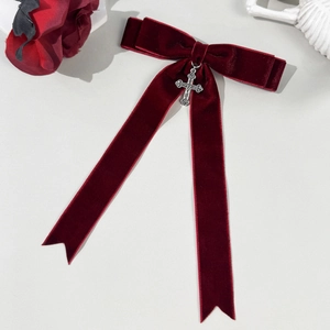 Close-up of gothic burgundy velvet bow hair clip with silver cross pendant detail