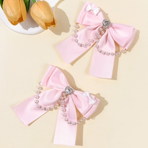 Dettaglio fermagli per capelli con fiocchi rosa, catene di perle e strass a cuore