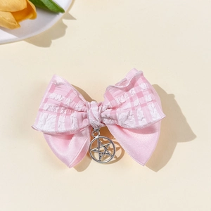 Gros plan sur une pince à cheveux nœud à carreaux roses avec pendentif étoile argent