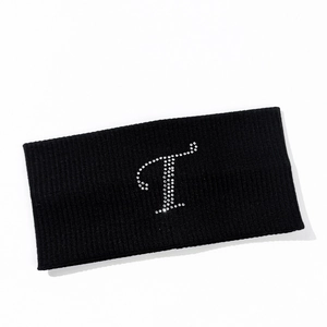 Detailed close-up of a black ribbed knit yoga headband with a rhinestone letter T decoration