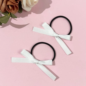 Détail de deux nœuds en satin blanc sur des élastiques noirs sur une surface rose