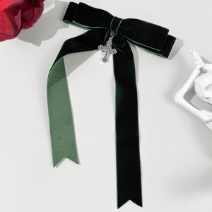 Detail of dark green velvet bow hair clip with vintage silver cross pendant and ribbons