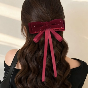 Close-up of velvet wine red bow hair clip with white polka dots on wavy hair