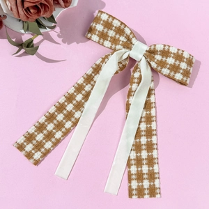 Dettaglio dell'elegante fiocco pied de poule con nastro crema su sfondo rosa