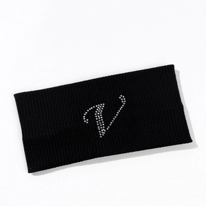 Close-up of black elastic yoga headband with rhinestone letter V on knit fabric