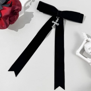 Detailed macro view of black velvet bow hair clip with silver gothic cross pendant decor