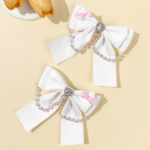 Dettaglio di fermagli per capelli a fiocco in raso bianco con strass a cuore e perle