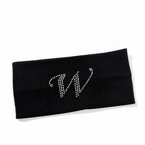 Macro detail of elastic black knitted sports headband featuring silver rhinestone letter W