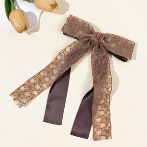 Close-up of the delicate floral lace texture and brown satin ribbon on the bow hairclip