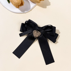 Nahaufnahme einer schwarzen Satin-Schleife mit einem gravierten goldenen Herzanhänger