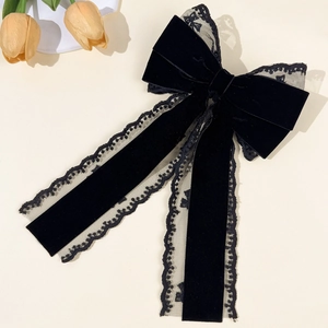 Detailed view of elegant black velvet hair bow with lace edges and long flowing ribbons