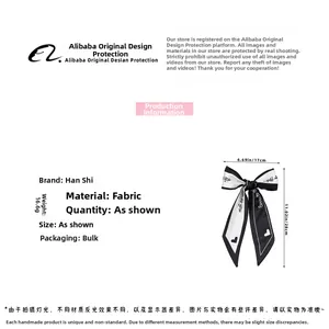 Detail view of a black and white bow hair clip with letter prints measuring 28x17cm