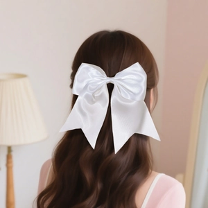 Elegant large white satin bow hair clip with long ribbons shown on long wavy hair