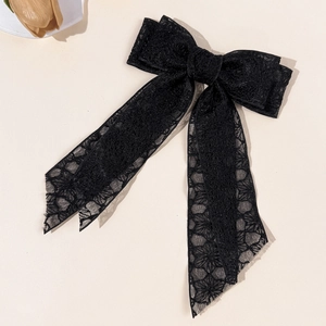 Close-up of black floral lace bow hair clip with intricate embroidery on beige background