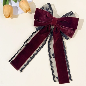 Detail of dark red velvet bow hair clip with black lace trim and long flowing ribbons
