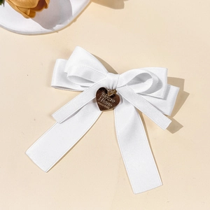 Details der eleganten weißen Satin-Haarschleife mit goldenem Herzanhänger und Gravur