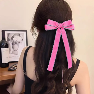 Pink bow hair tie with long ribbons and green wavy edges on brown curly hair