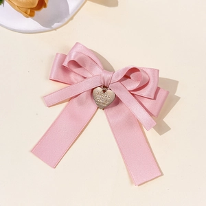 Nahaufnahme einer rosa Satin-Haarspange mit einem goldenen Herz-Metallanhänger