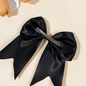 Detailed back view of a large black satin bow hair clip with a silver metal duckbill clip