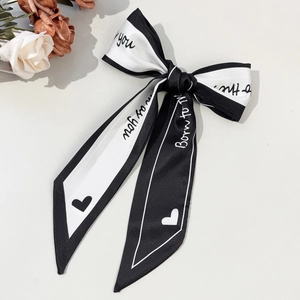 Detailed view of the silk satin bow hair clip with elegant letter prints and heart pattern