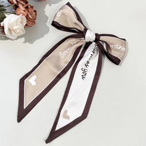 Detail of elegant satin bow hair clip with letter print and French chic color block