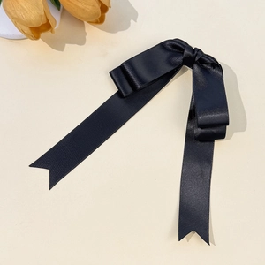 Detail of elegant black satin ribbon bow hair clip with chic swallowtail ends and soft sheen