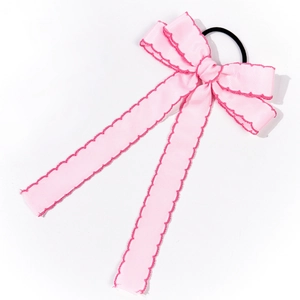 Detail of pink bow hair scrunchie with dark pink wavy edge stitching and long ribbons