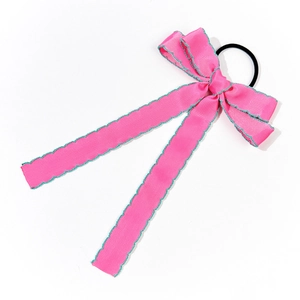 Detailed macro view of pink bow hair tie with green scalloped edges on white background