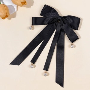 Detail of elegant black satin bow hairclip with long ribbons and pearl drop pendants