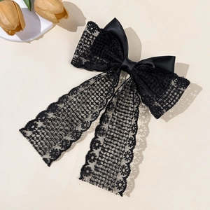 Detailed macro view of black lace bow hair clip with vintage floral patterns and satin texture