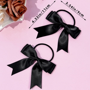 Lot de deux chouchous nœuds en satin noir style ballet de 11 cm sur un fond rose doux