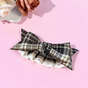 Detail of a brown plaid hair bow clip with delicate white lace trim on pink background