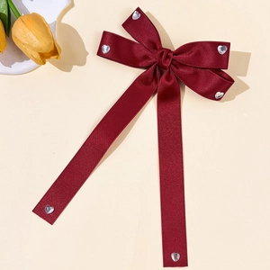 Détail de la barrette en satin bordeaux avec strass en cœur et élégantes longues pompons