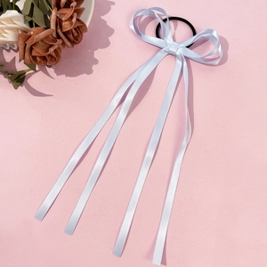 Dettaglio dell'elastico per capelli con fiocco in raso celeste e nastri lunghi su rosa