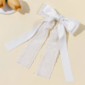 Detailed close-up of the elegant white lace and satin ribbon bow hair clip with floral patterns