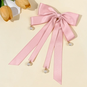 Detail of pink satin bow hair clip with hanging pearls and elegant long ribbons