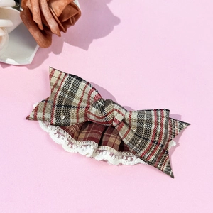 Detail of red-brown checkered bow hair clip with white lace trim and small rhinestones
