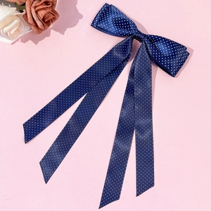 Dettaglio del fiocco in raso blu scuro a pois con lunghi nastri su sfondo rosa