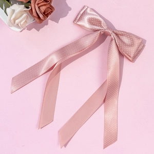 Elegante fiocco per capelli in raso rosa a pois con lunghi nastri su sfondo floreale