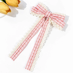 Detailed view of pink plaid bow hair clip with lace edges and long hanging ribbons