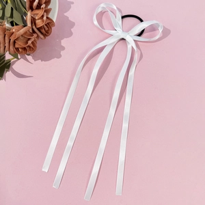 Dettaglio di elastico per capelli con fiocco in raso bianco e nastri su sfondo rosa