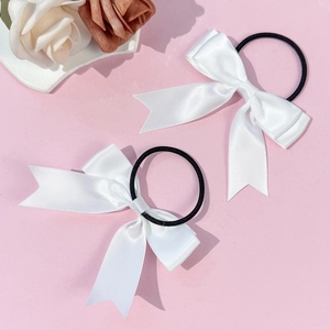 Lot de deux chouchous à nœud en satin blanc avec élastiques noirs sur fond rose