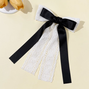 Detail of elegant black satin and white floral lace double bow hair clip with long ribbons