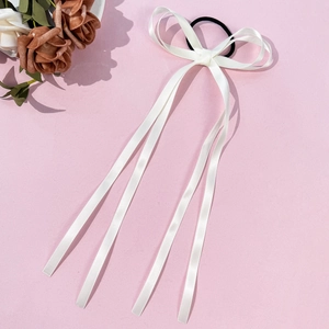 Dettaglio di un elastico in raso bianco crema con fiocco e lunghi nastri su rosa