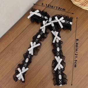 Barrette Lolita en dentelle noire avec petits nœuds blancs sur fond de bois