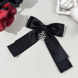 Macro shot of black satin bow hair clip with silver pentagram pendant in gothic style