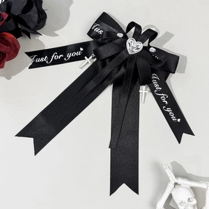 Close-up of gothic black satin bow with silver heart rhinestone and cross pendants