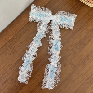 Détail d'une pince à cheveux en dentelle blanche avec nœuds en soie bleue et rubans fins